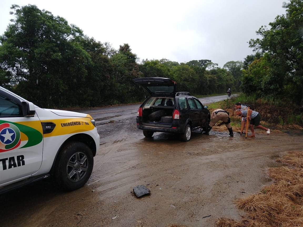 Sargento da Polícia Militar Rodoviária ajuda motorista a trocar pneu na SC-477