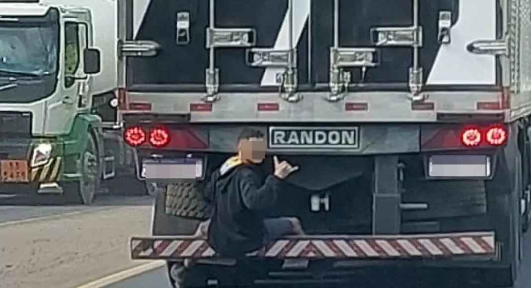 Homem é flagrado se segurando na traseira de caminhão e fazendo ‘hang loose’ na BR-470